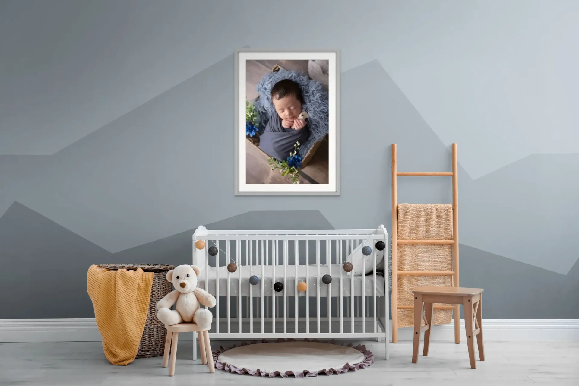 Baby boy nursery with his newborn portrait framed and hanging over the crib.