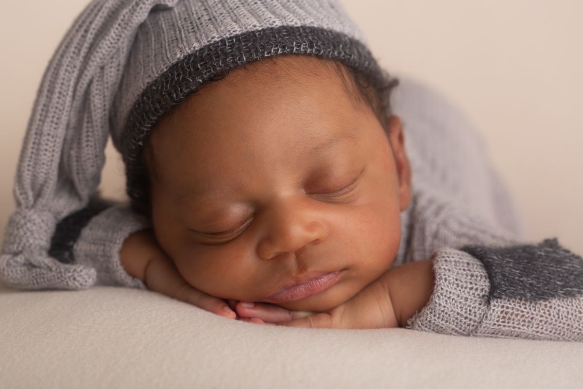 African American Newborn boy sleeping chin on hands