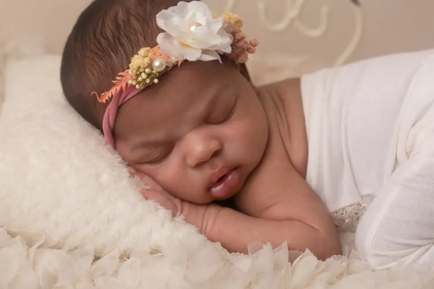 Glendale newborn portrait of a girl with chin on hands in peach theme.