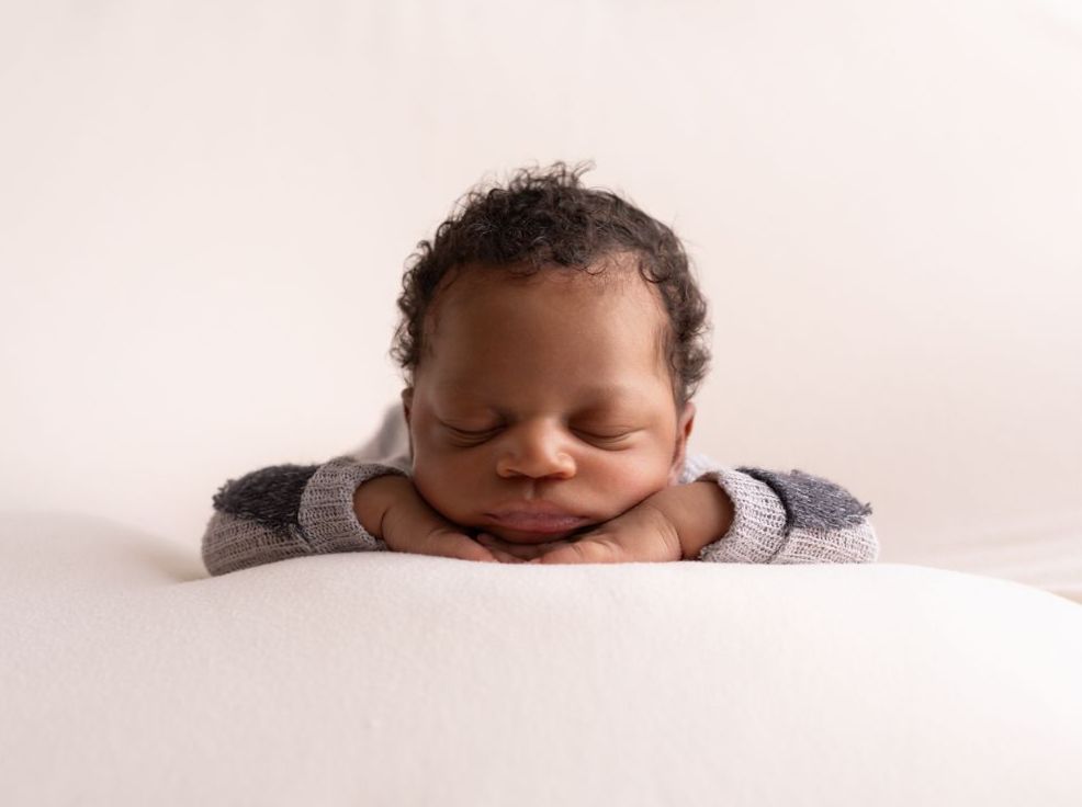 Newborn Boy in chin on hands pose in grey sleeper in studio.