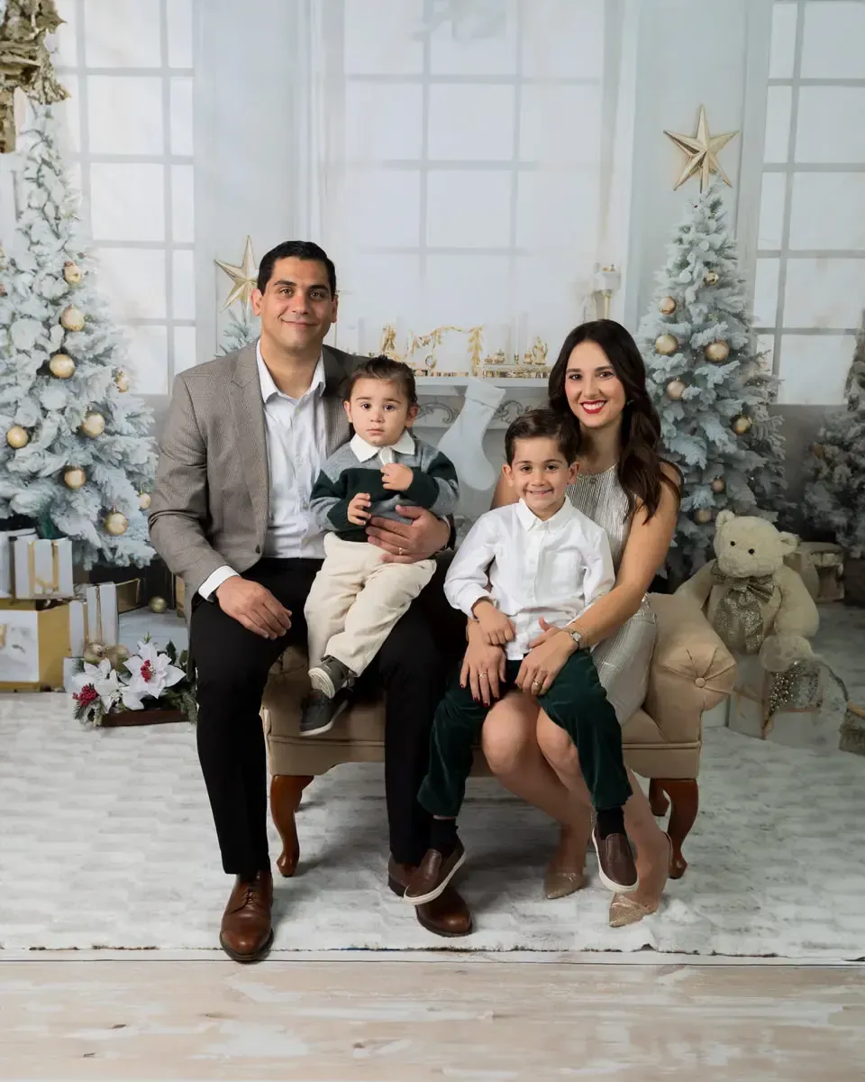 Young family in formal holiday portrait in white and silver living room.
