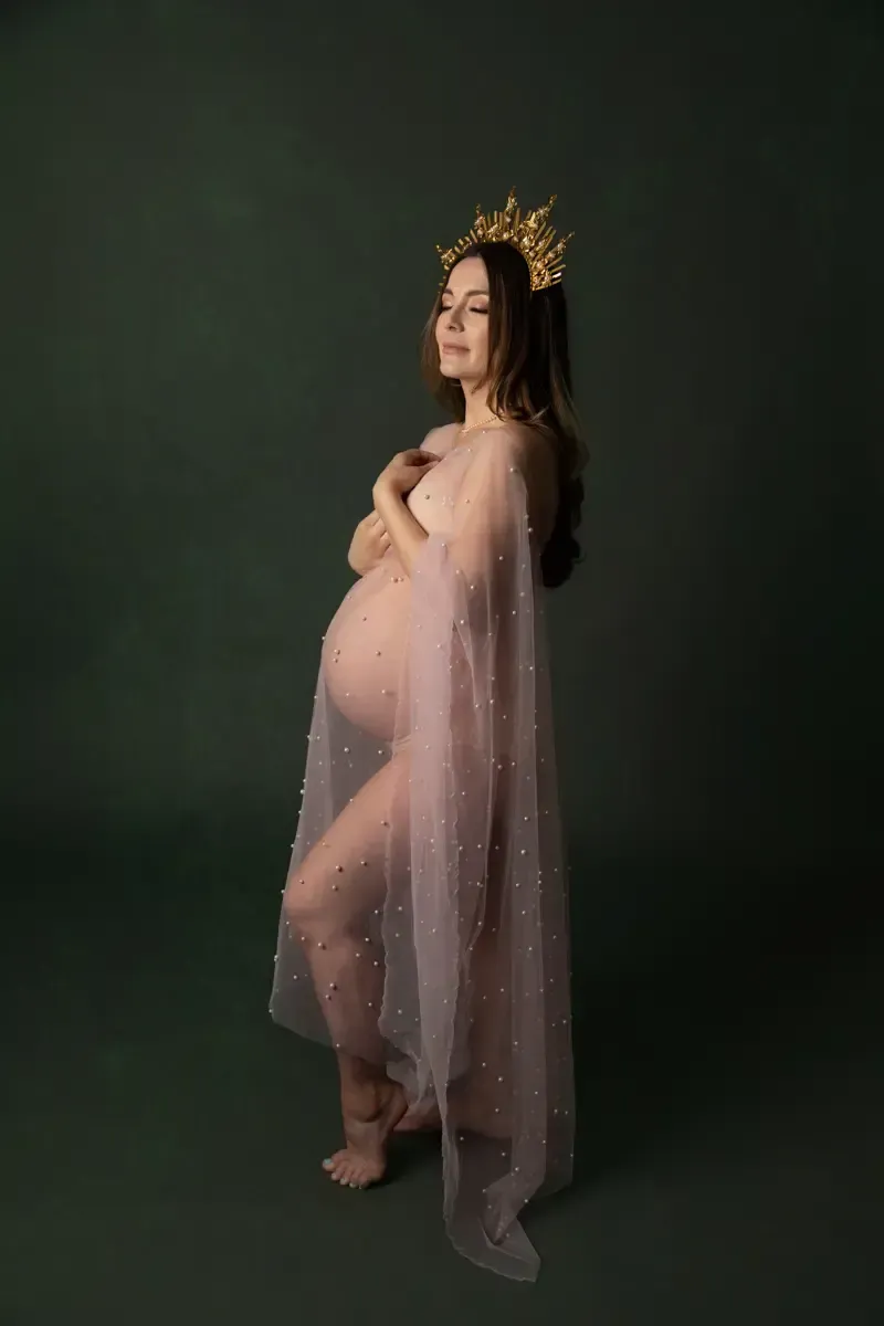 Pregnancy photos of woman wearing a crown. Draped in sheer fabric.