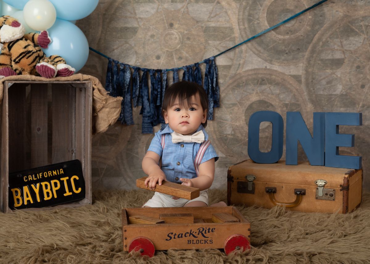 Baby boy in bow tie and antique blocks looking cute.