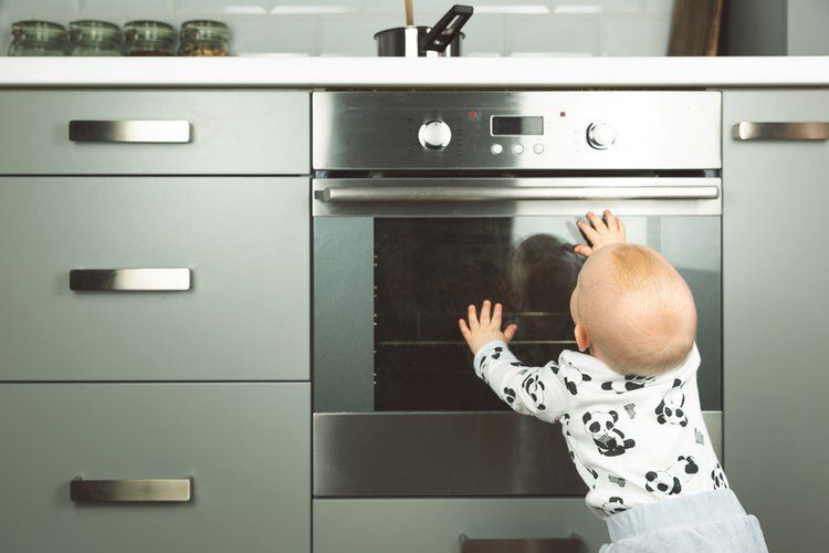 Baby standing near oven in kitchen
