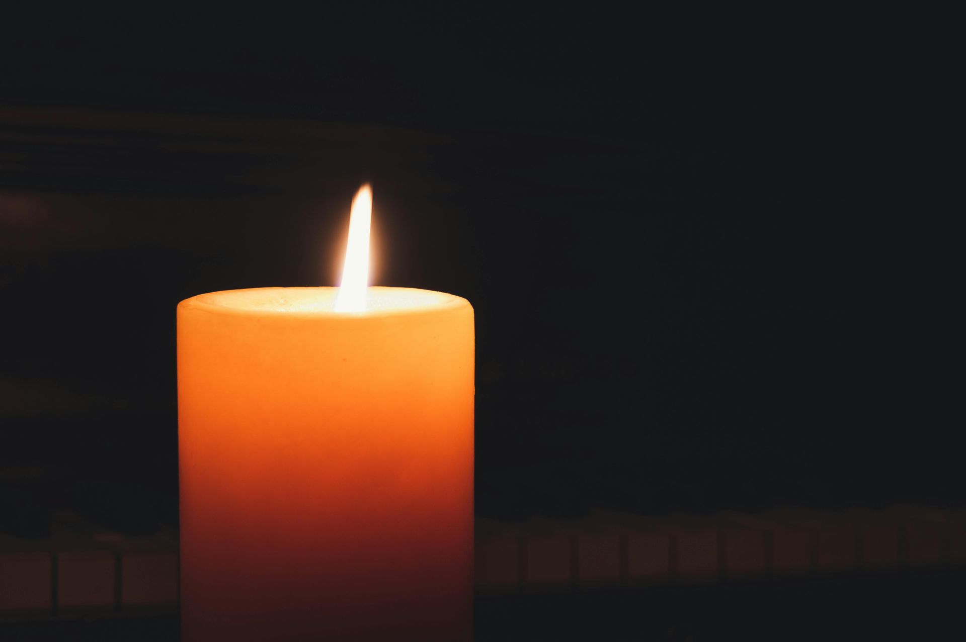 A lit candle on a dark background