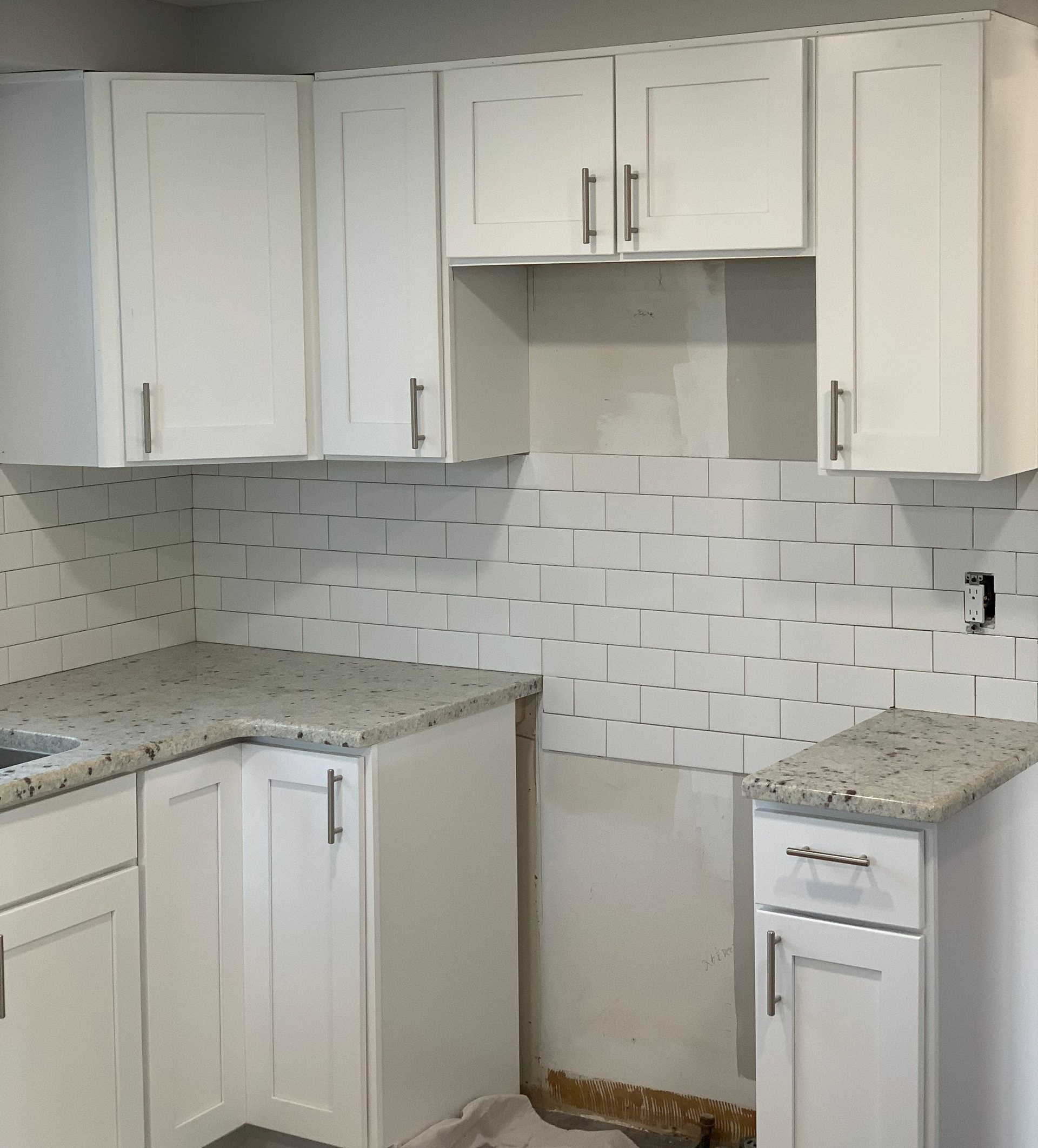 Person standing on newly installed gray carpet, boxes of carpet tiles nearby, doorway on right.