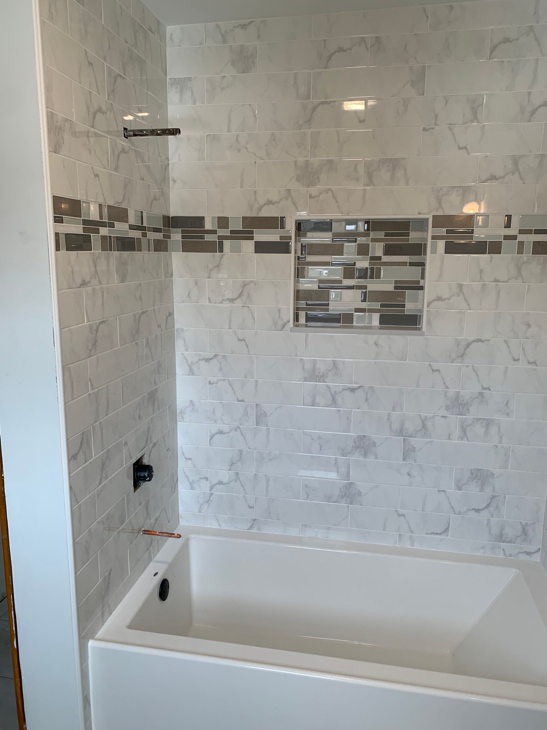 Person in gloves placing tile on a mortar bed with level and mallet nearby.