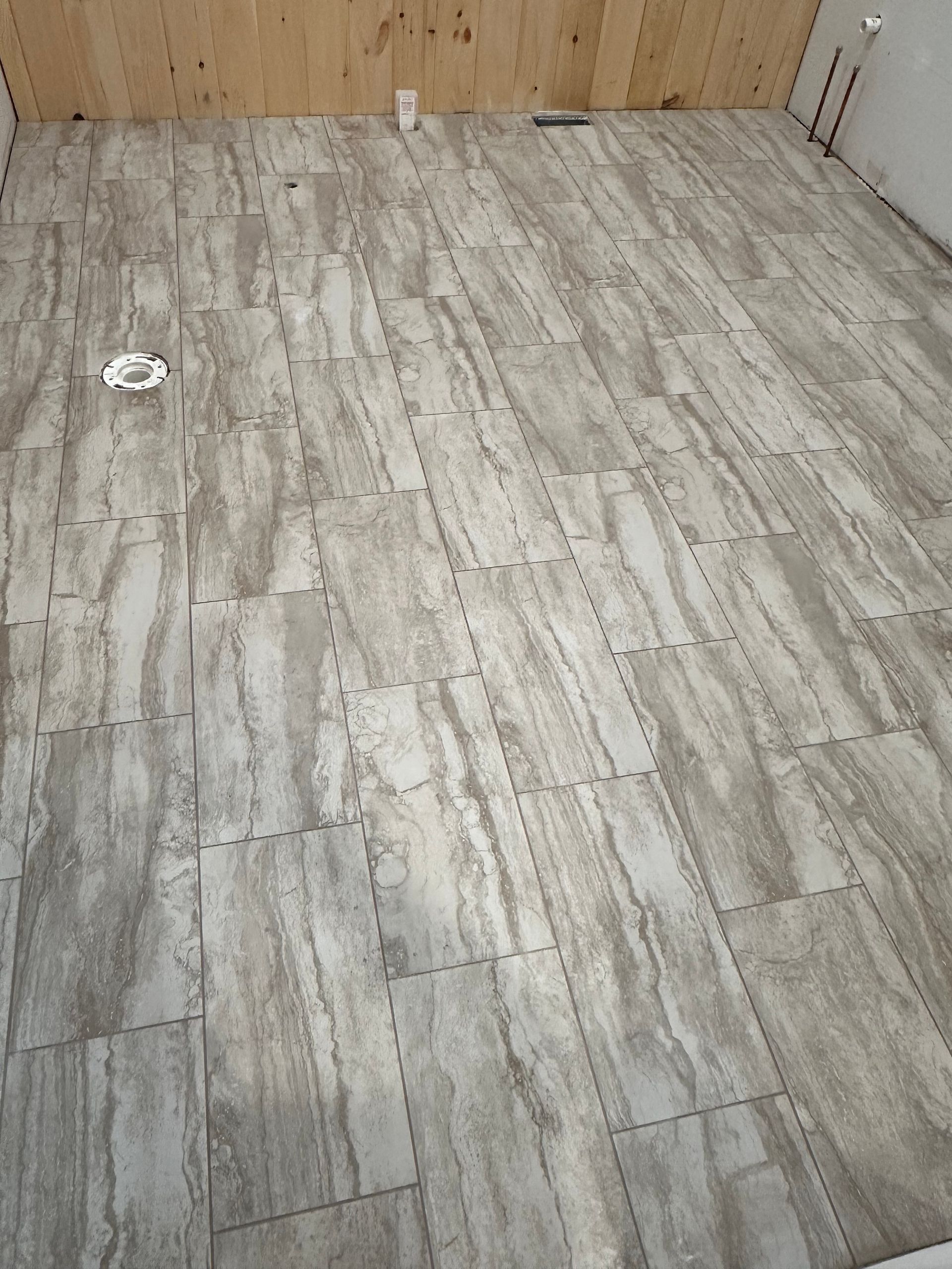 A man is laying tiles on the floor in a living room.