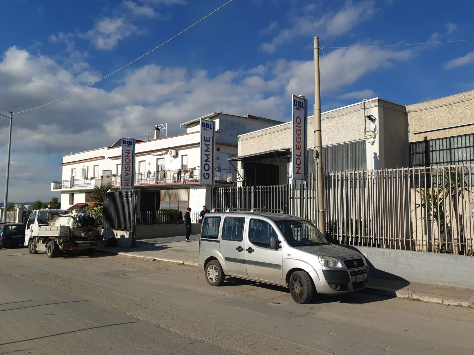 Un furgone bianco è parcheggiato davanti a un edificio con un cartello che dice 