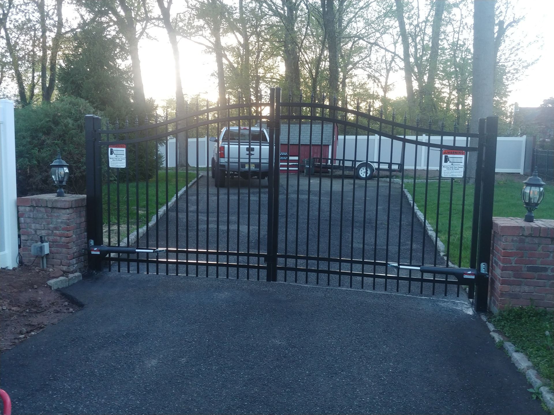 A car is parked in a driveway behind a wrought iron gate