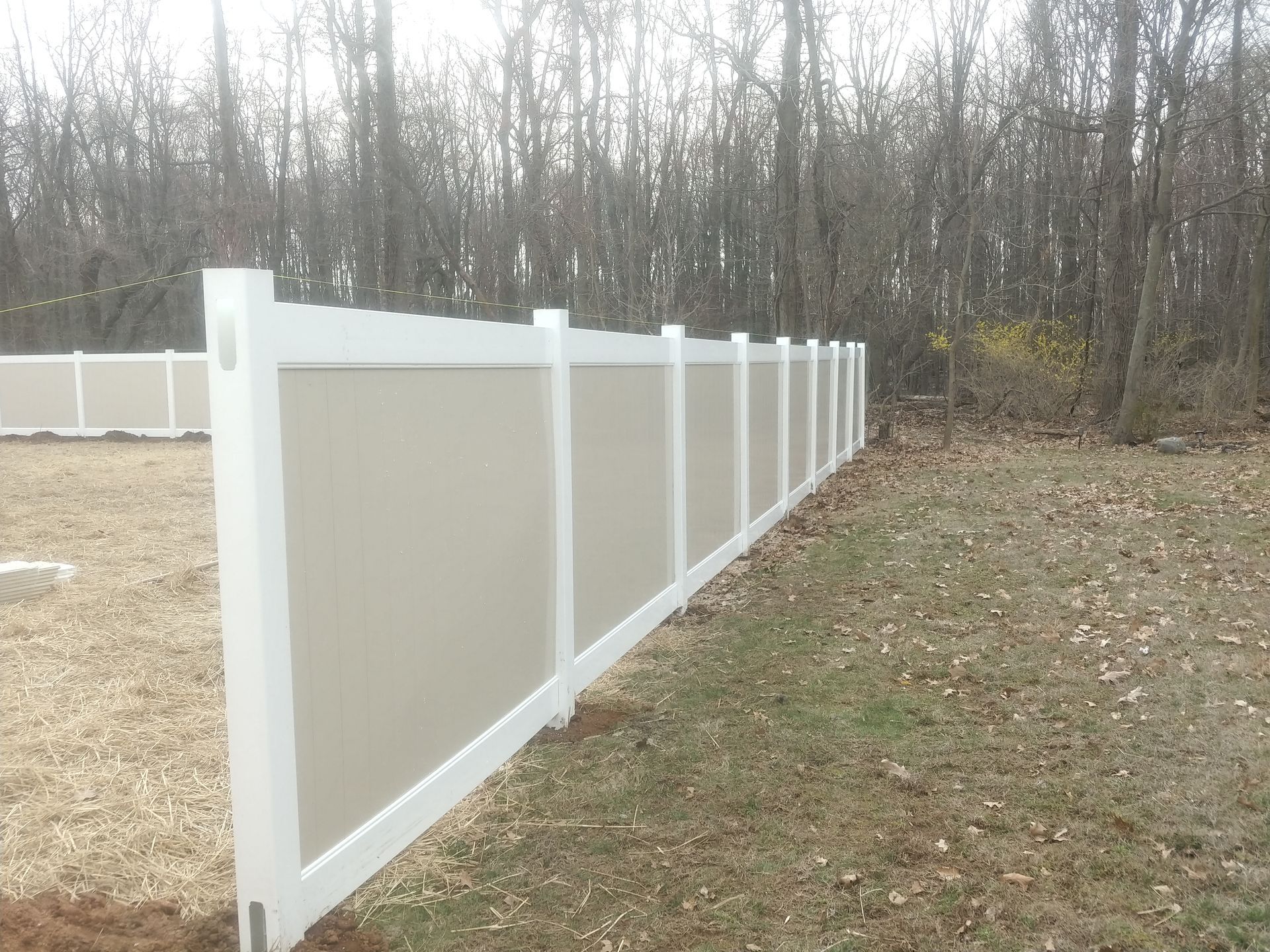 A white fence surrounds a grassy area with trees in the background