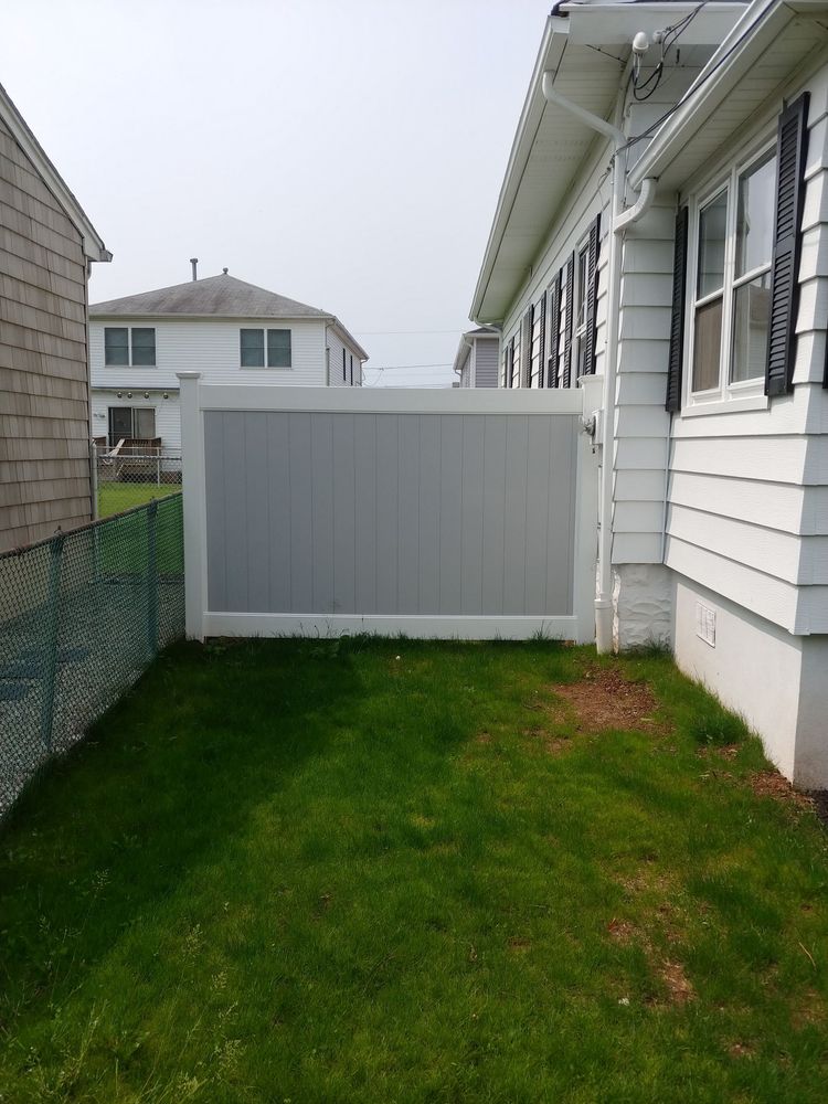 A white fence with a pergola and gate in front of a house.