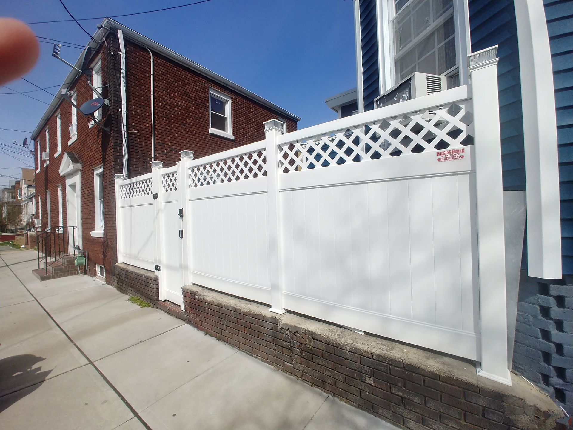 A white fence is in front of a brick house