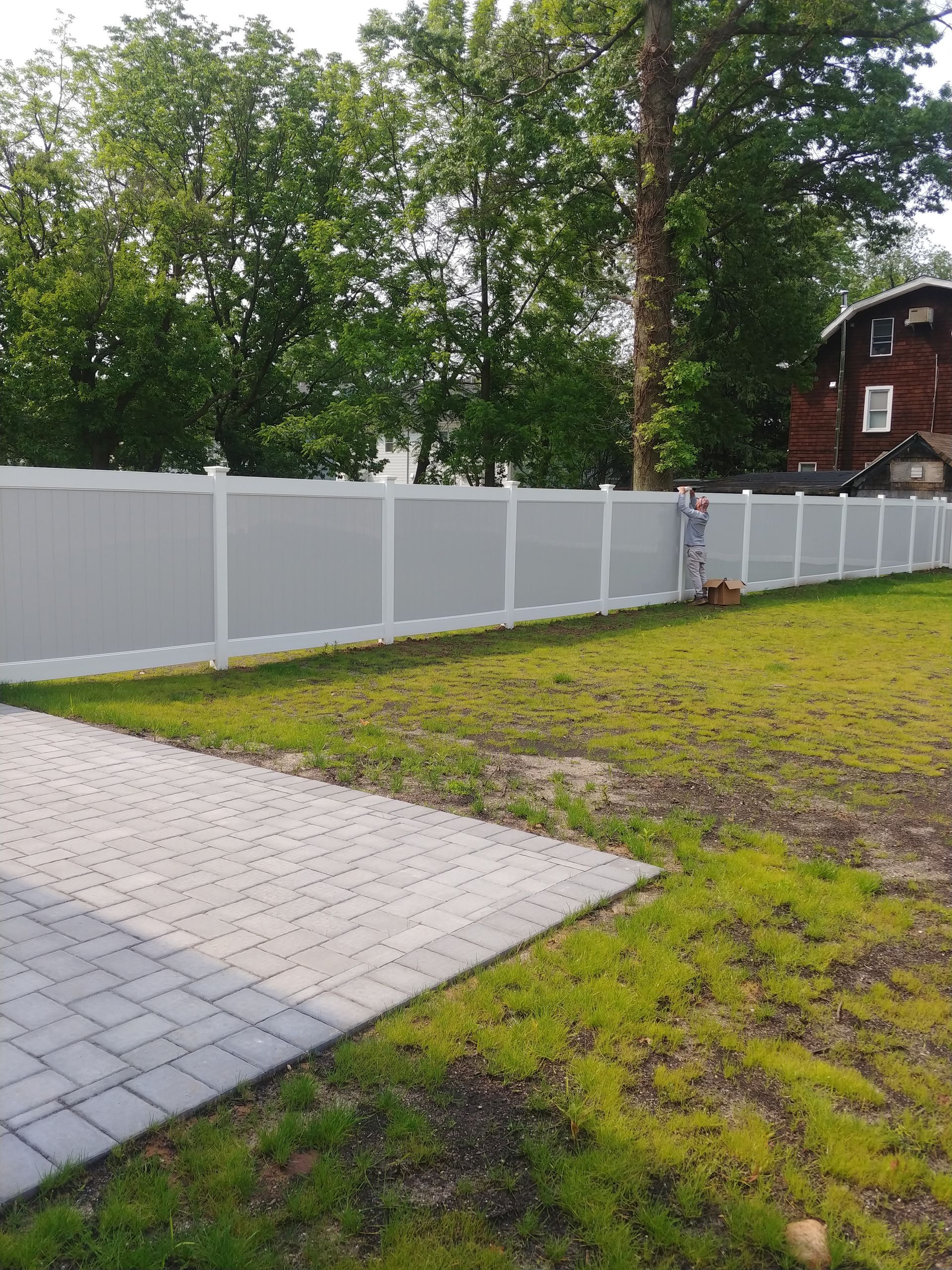A white fence surrounds a lush green yard in front of a house.
