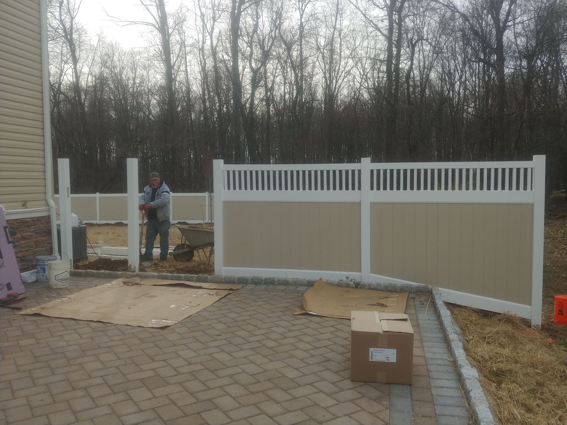 A man standing next to a fence with a box in front of it
