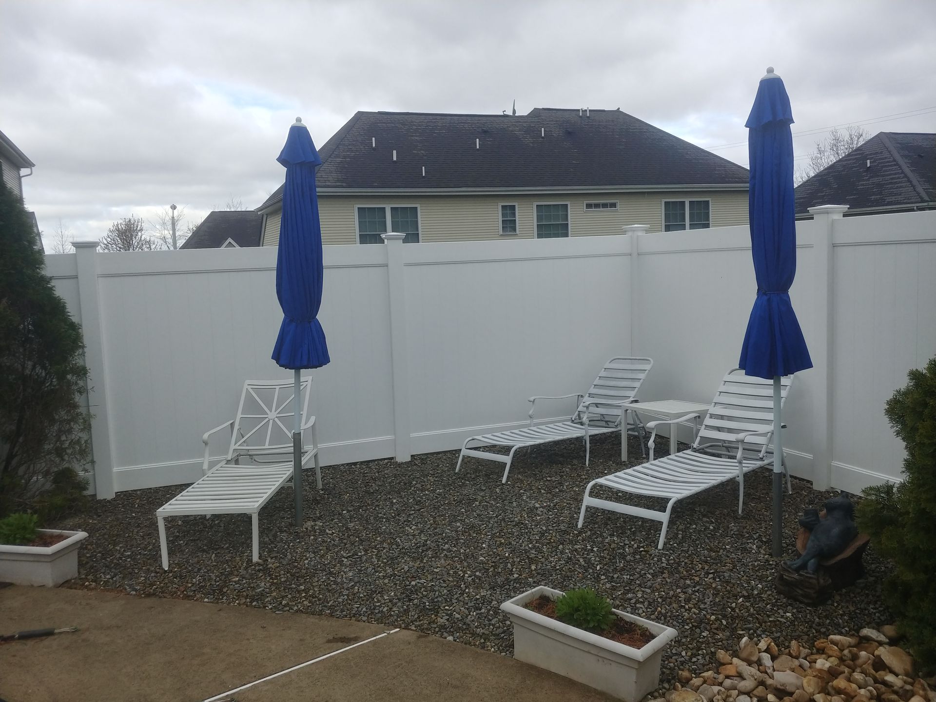 A white fence with blue umbrellas and lounge chairs