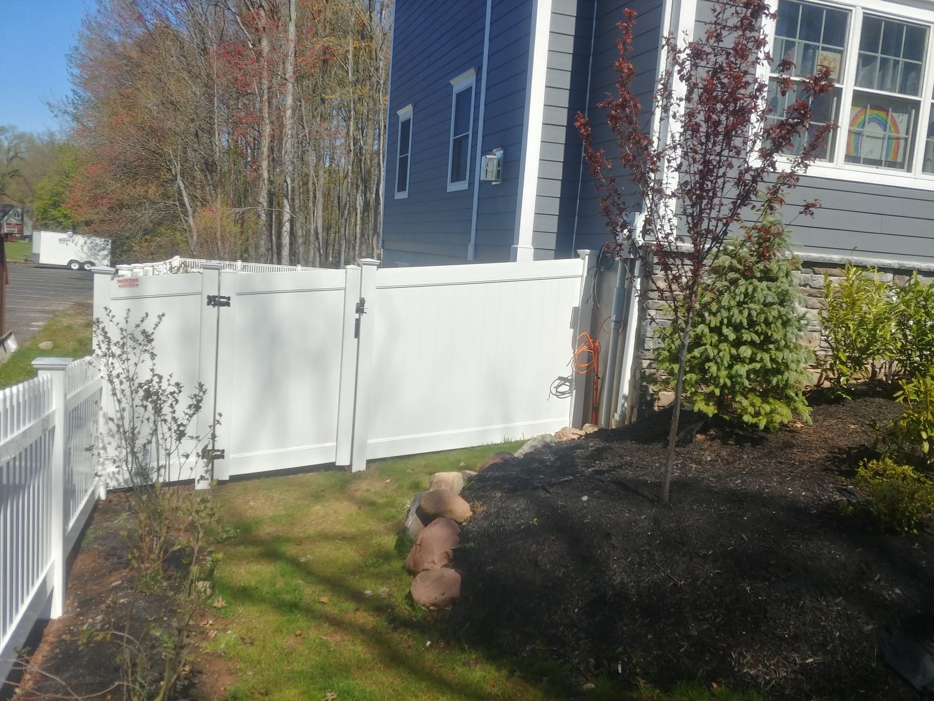 A white fence is in front of a blue house