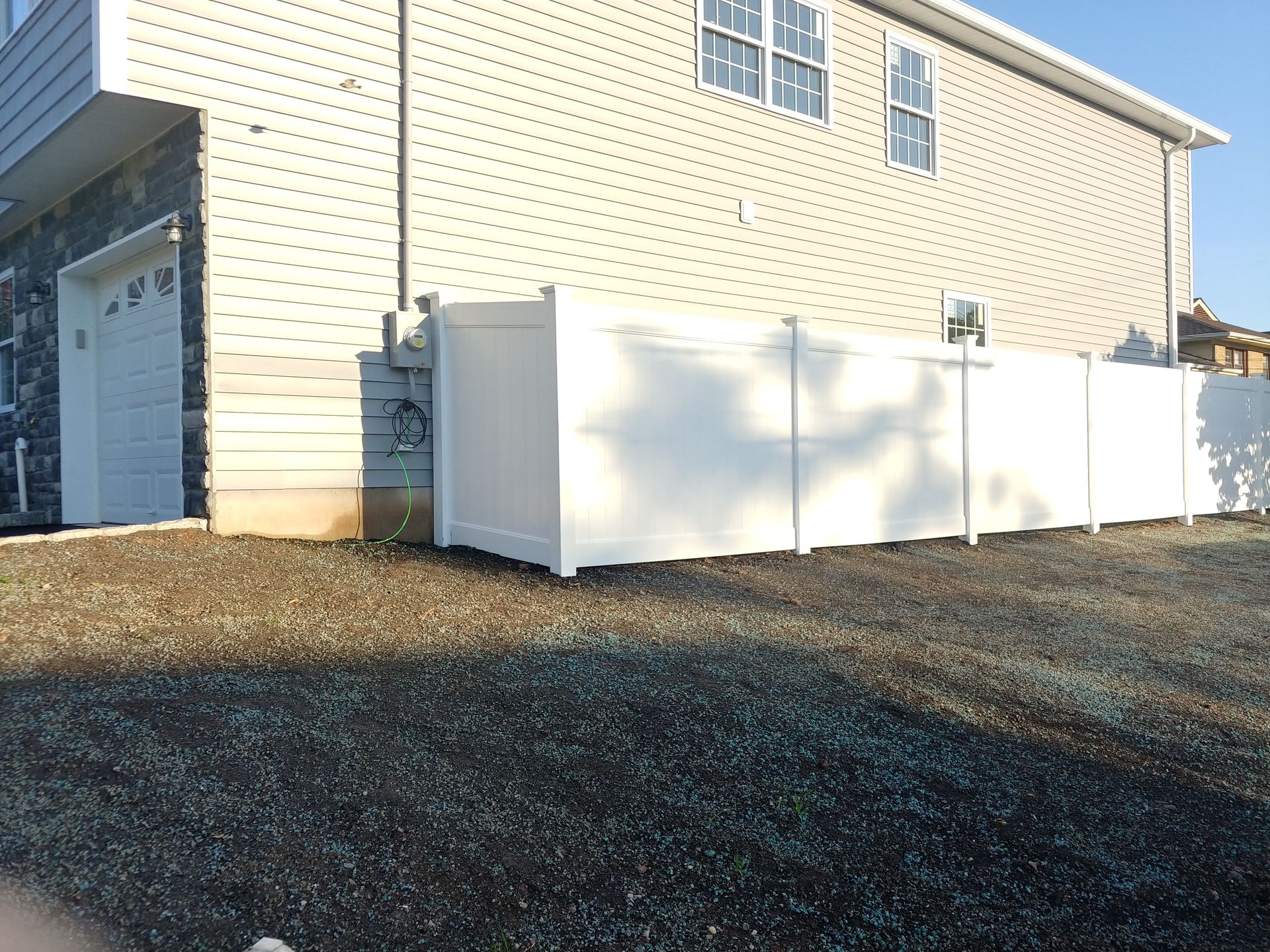 A white fence is sitting in front of a house.