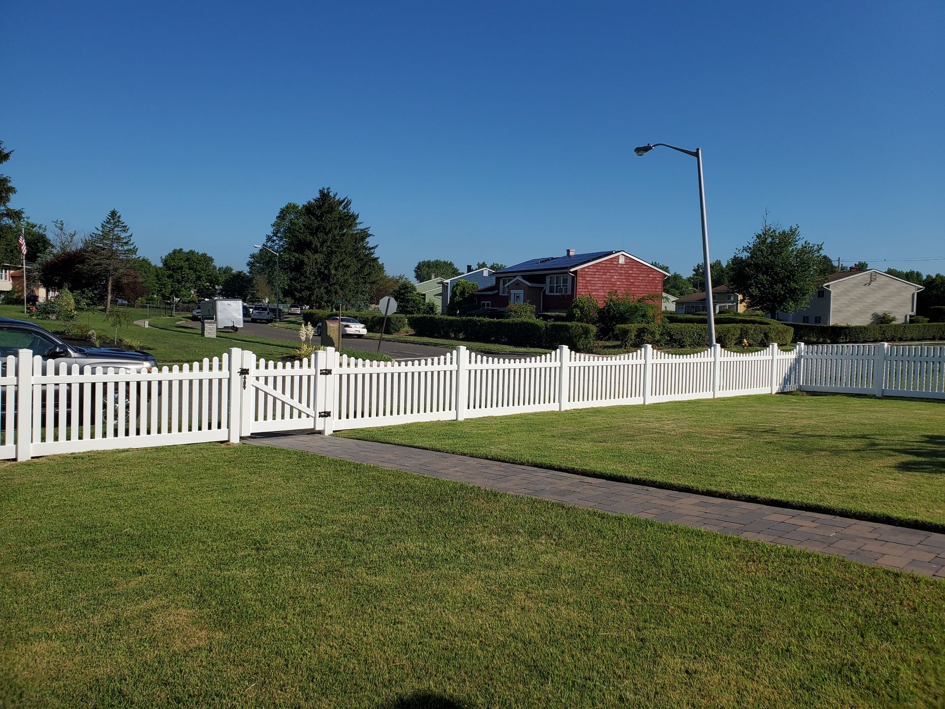 A white picket fence surrounds a lush green yard.