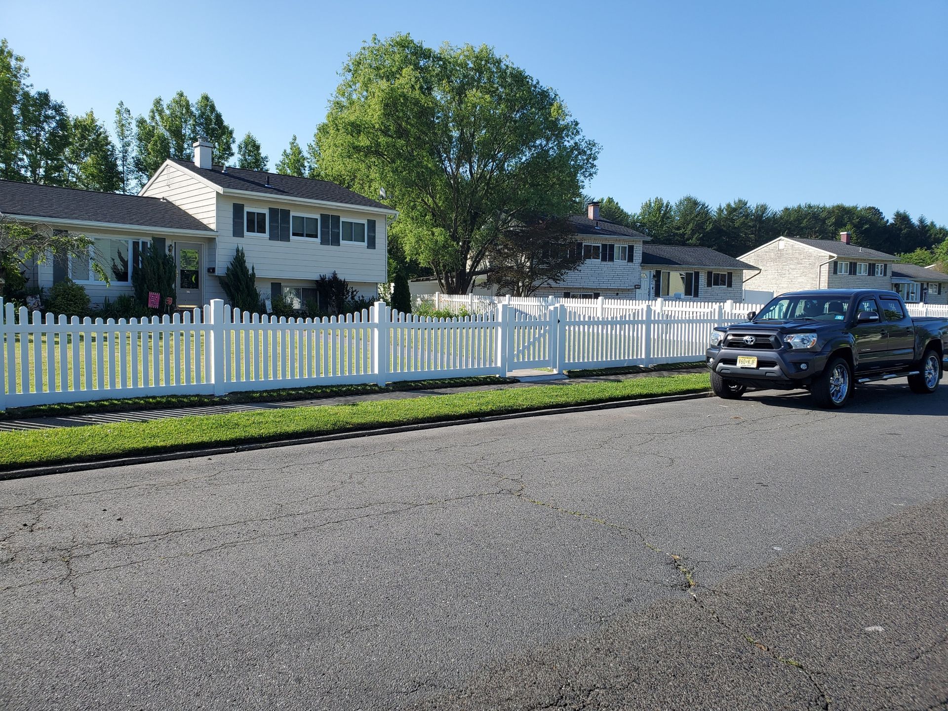 A black truck is parked in front of a white picket fence