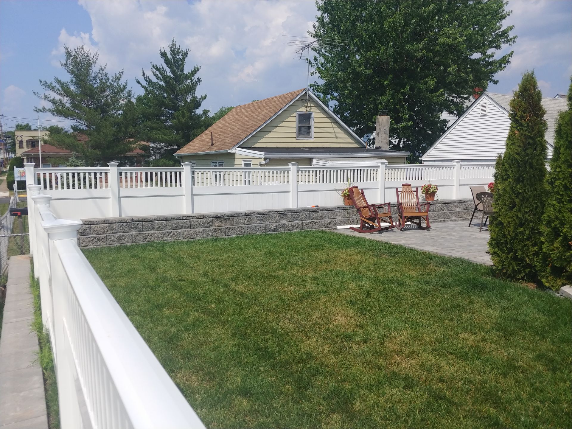 A white fence surrounds a lush green yard