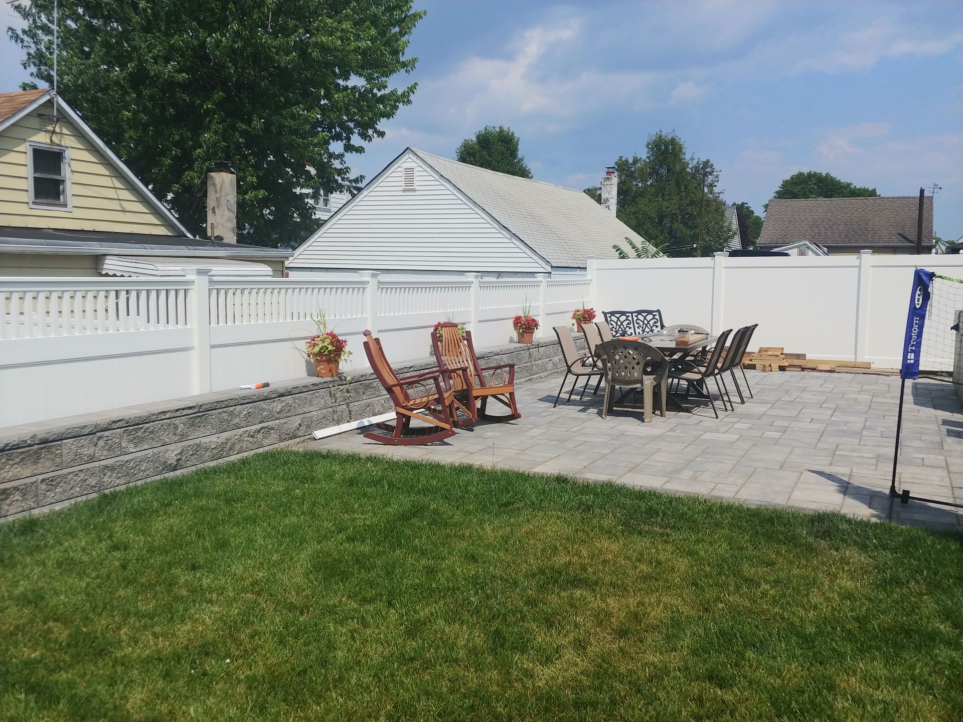 A backyard with a table and chairs and a white fence