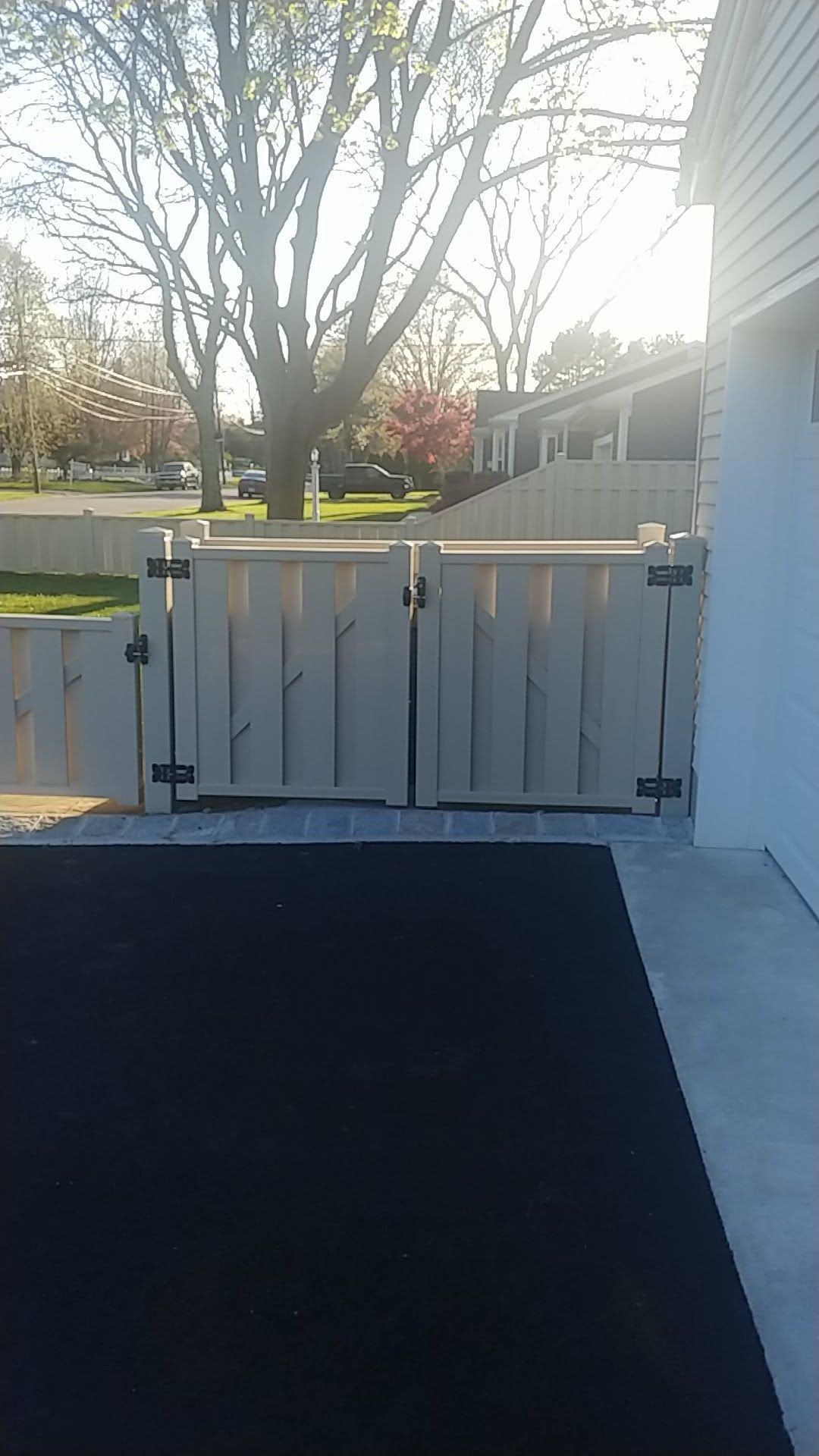 A white fence is sitting next to a black rug on a patio.