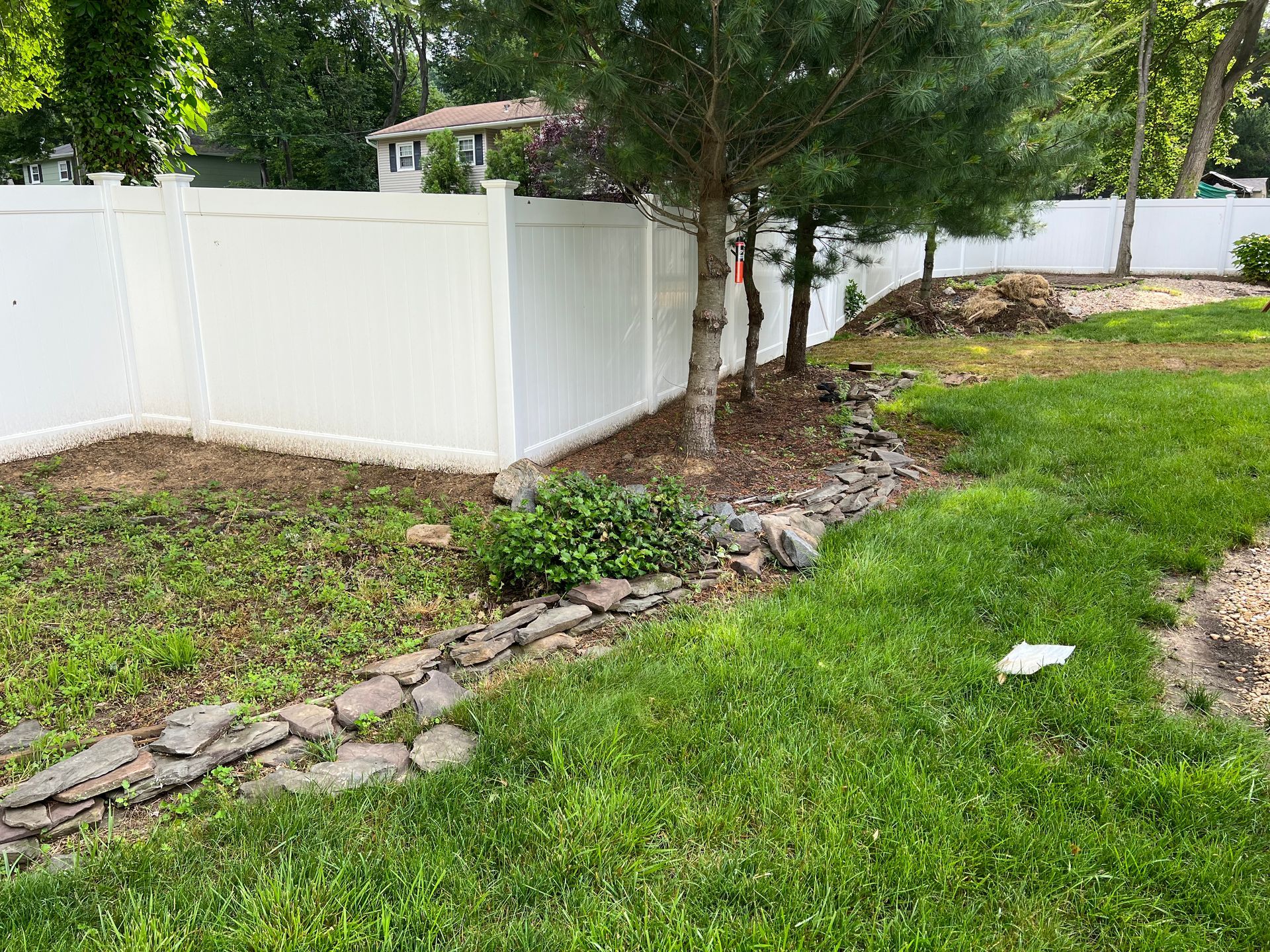 A white fence surrounds a lush green lawn in a backyard.