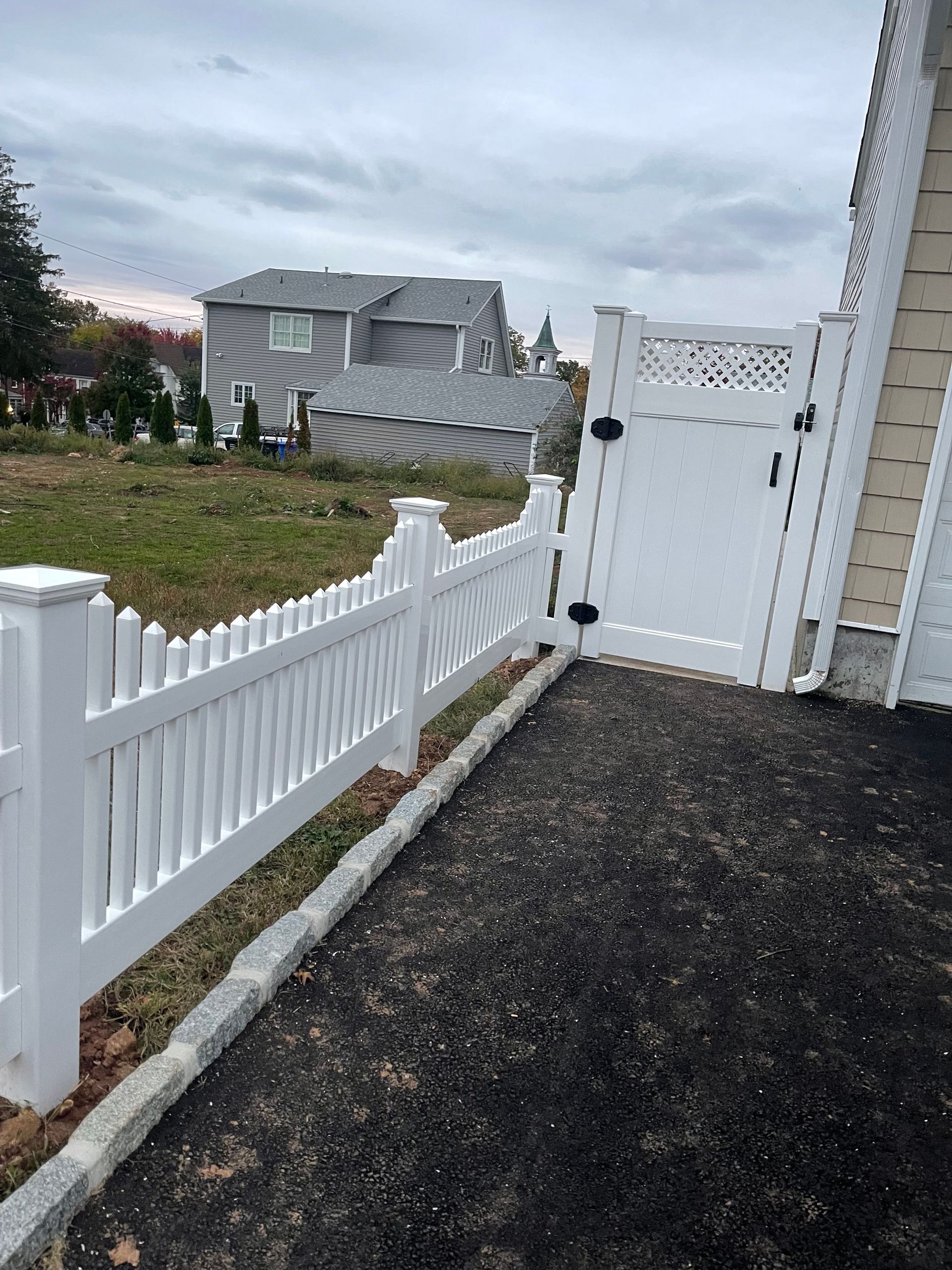 A white picket fence with a gate in front of a house.