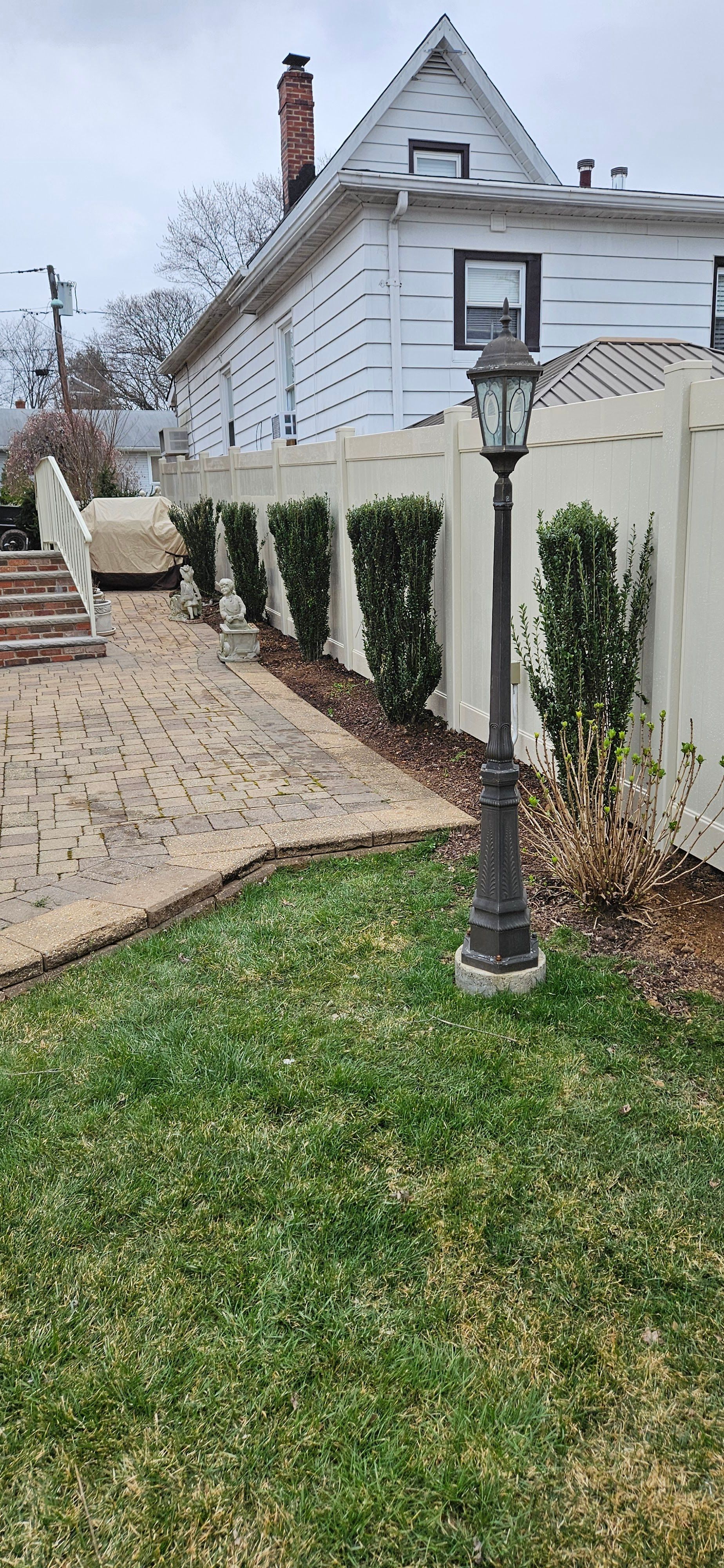 A wooden fence surrounds a gravel road with trees in the background.