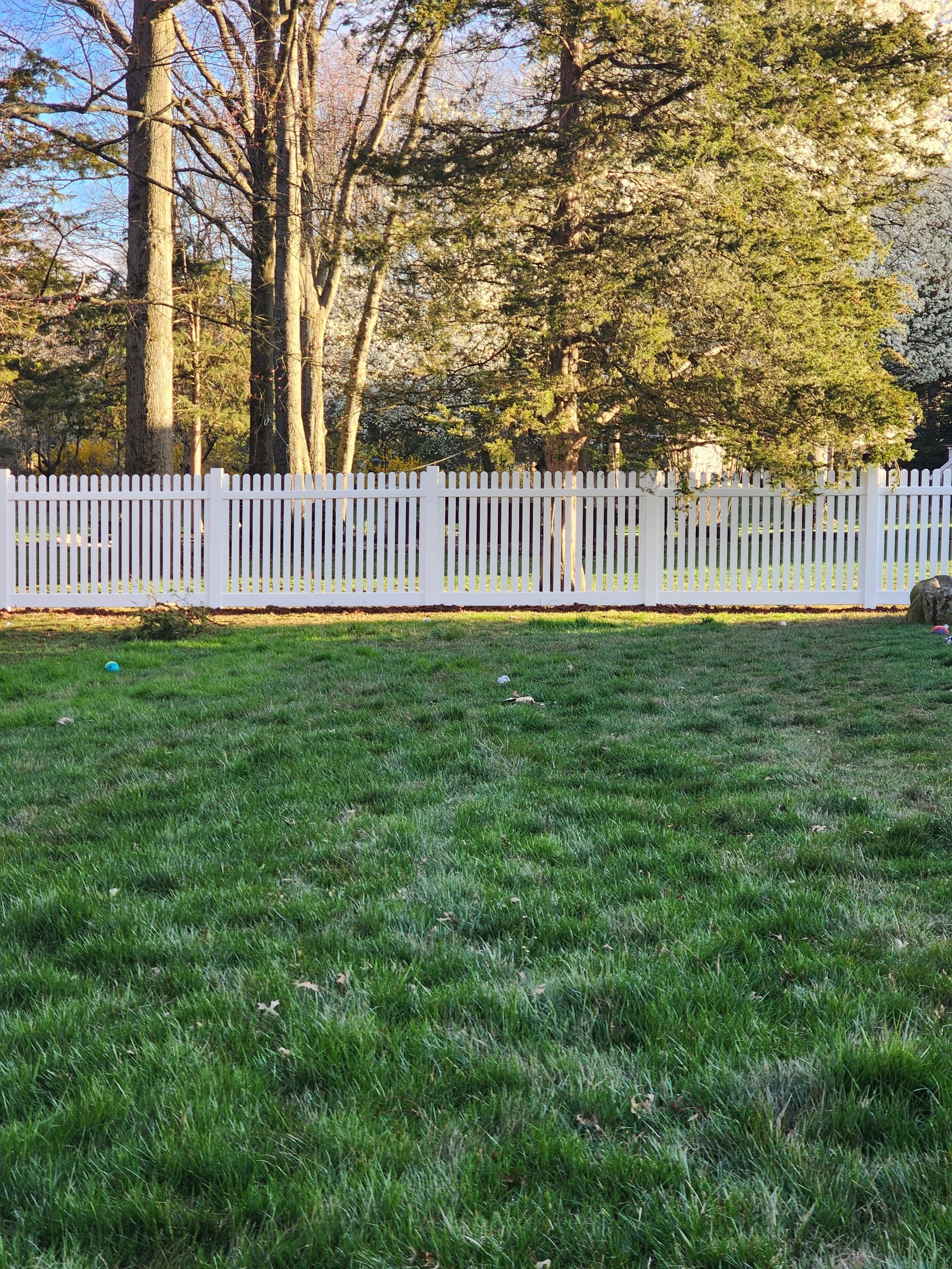 A white picket fence surrounds a lush green yard.