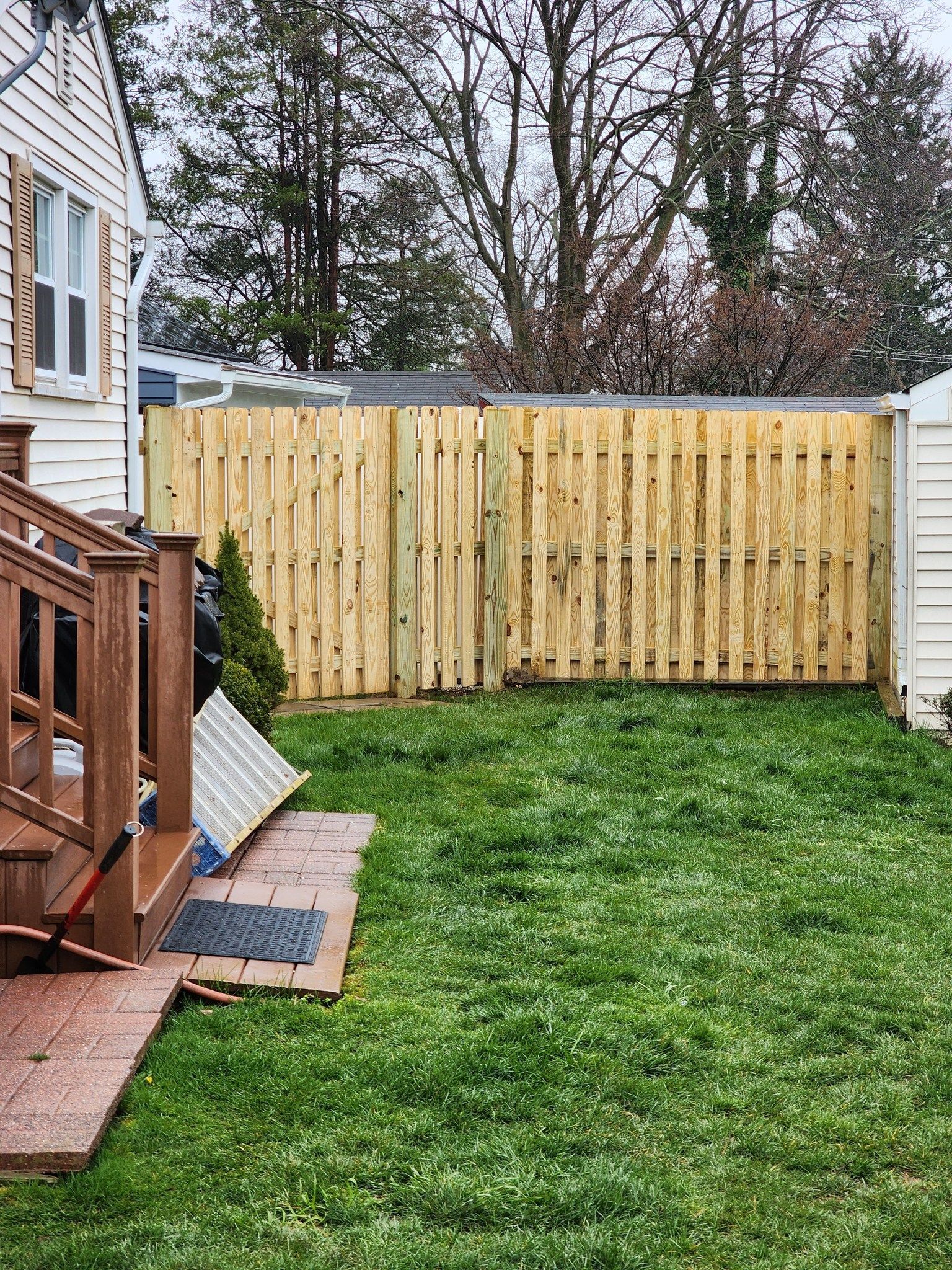 There is a wooden fence in the backyard of a house.