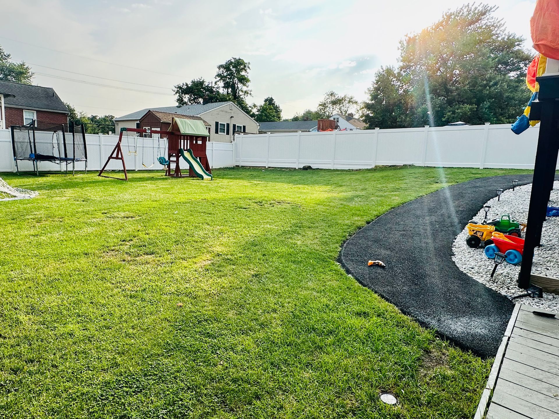 A person is spraying water on a playground in a backyard.