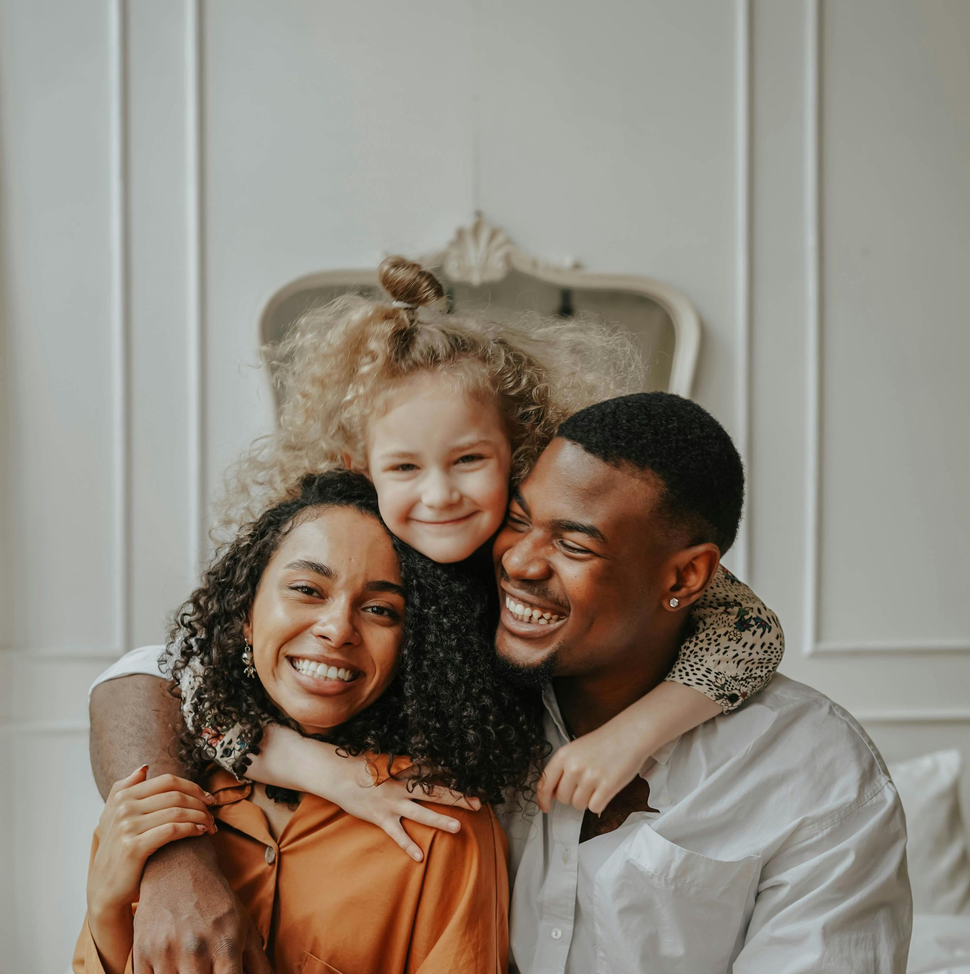 A little girl is holding a teddy bear in front of a family.