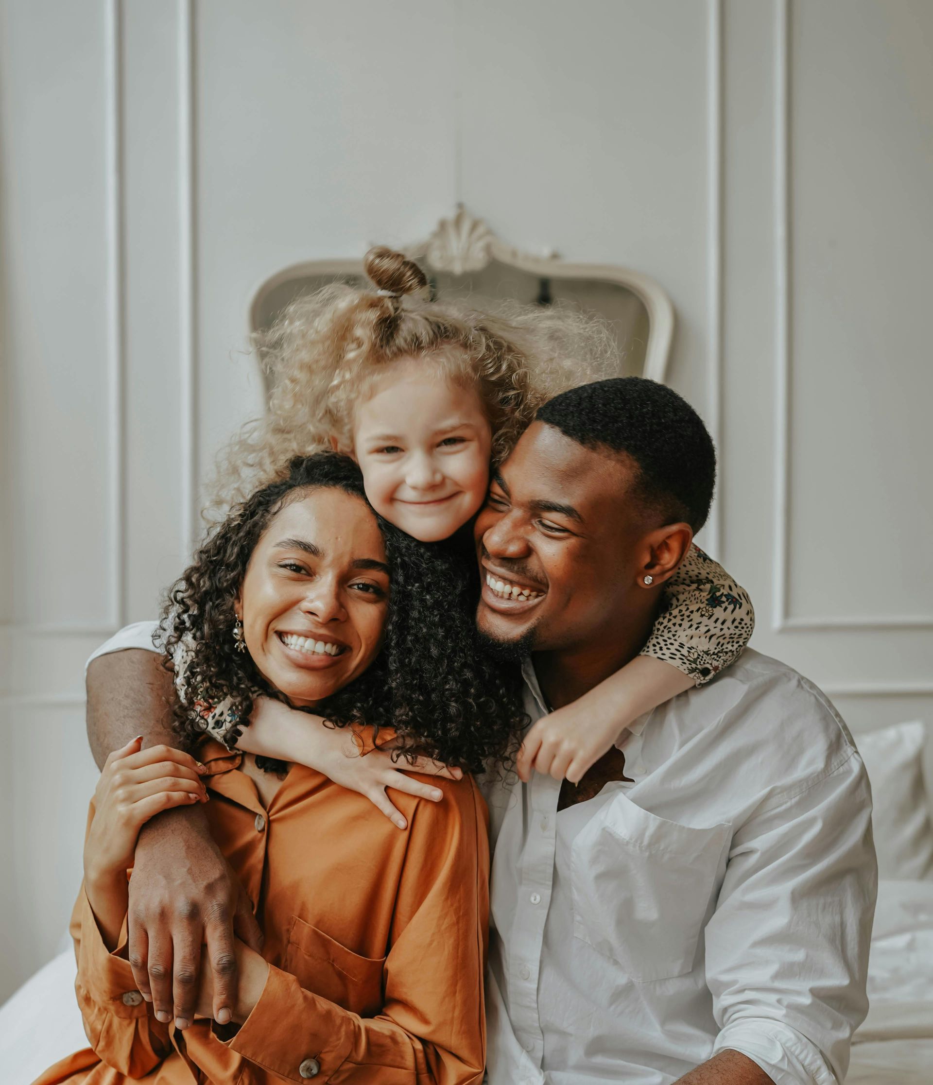 A little girl is holding a teddy bear in front of a family.