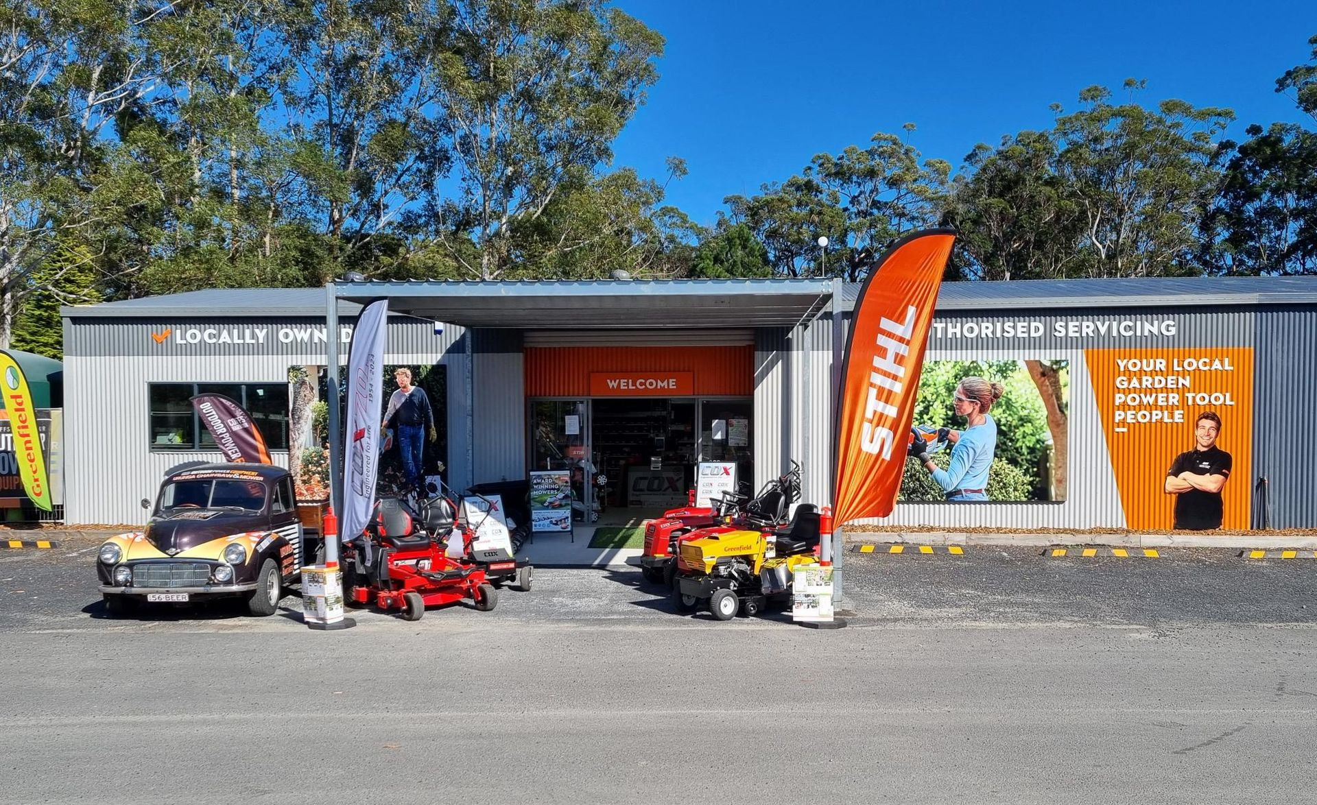Small hardware store with lawn mowers, a classic car, and STIHL signage — Urunga Chainsaw and Mower in Urunga, NSW