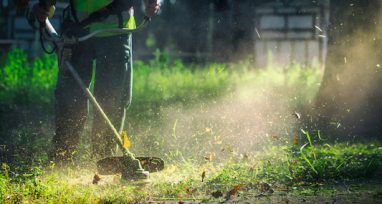 A Man is Mowing the Grass With a Lawn Mower — Urunga Chainsaw and Mower in Urunga, NSW