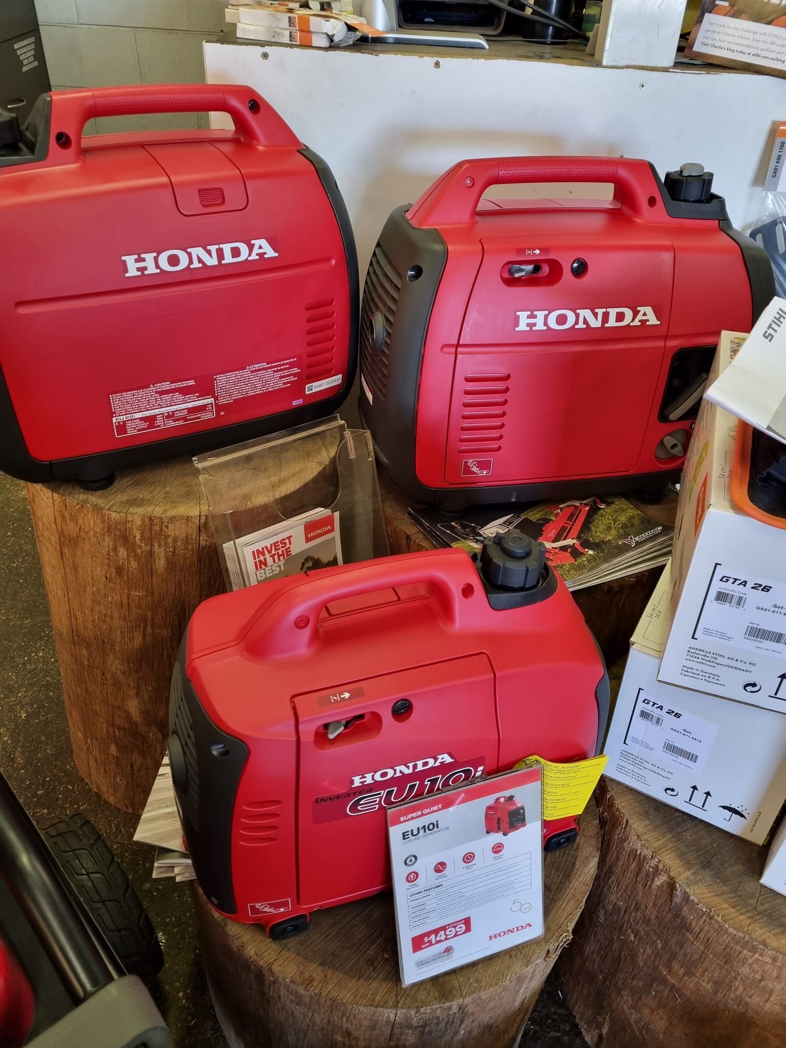 Two Red Honda Generators Are Sitting on Top of a Wooden Stump — Urunga Chainsaw and Mower in Urunga, NSW