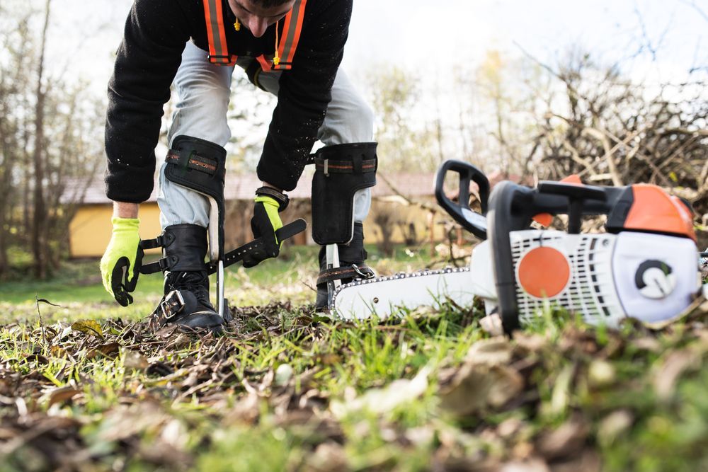 A Man is Using a Chainsaw to Cut a Hole in the Ground — Urunga Chainsaw and Mower in Urunga, NSW