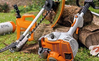 A Stihl Lawn Mower is Sitting on Top of a Log in the Grass — Urunga Chainsaw and Mower in Urunga, NSW