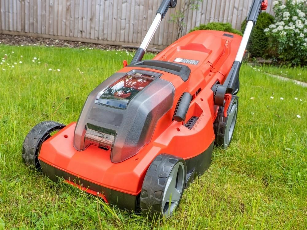 A Red and Black Lawn Mower is Sitting on Top of a Lush Green Lawn — Urunga Chainsaw and Mower in Urunga, NSW