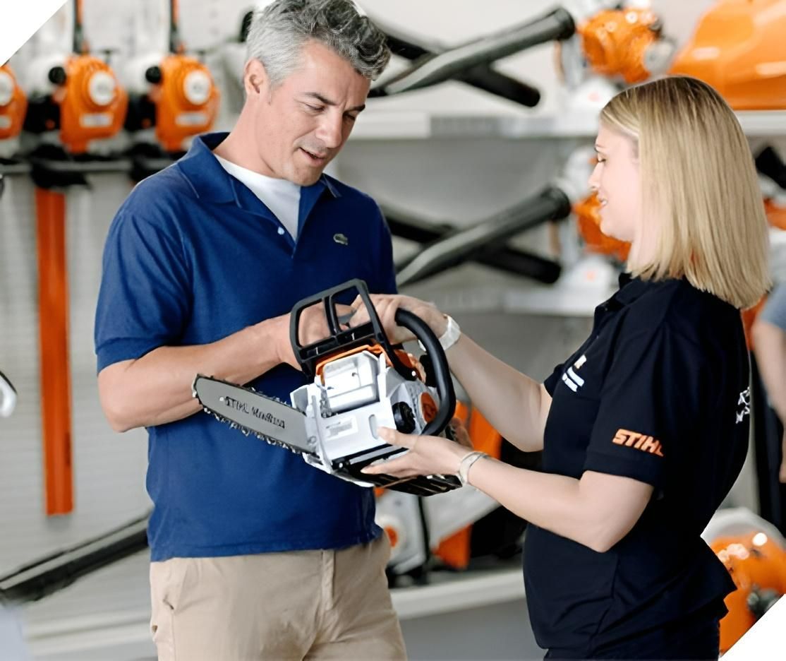 A Man and a Woman Are Looking at a Stihl Chainsaw — Urunga Chainsaw and Mower in Urunga, NSW