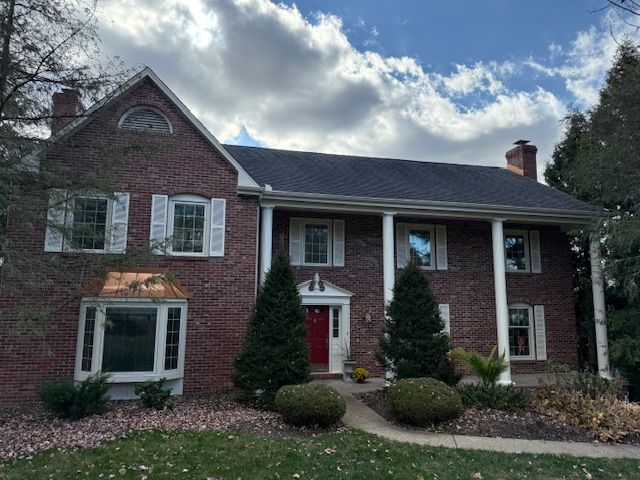 A large brick house with white shutters and a red door