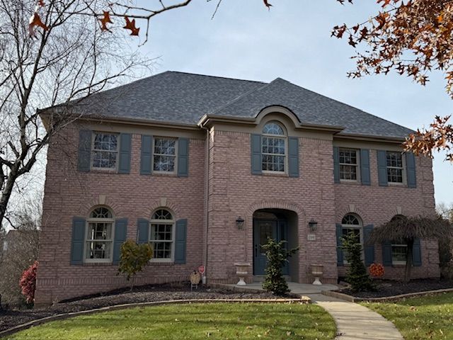 A large brick house with blue shutters and a gray roof