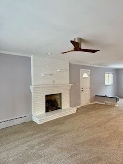 An empty living room with a fireplace and a ceiling fan.