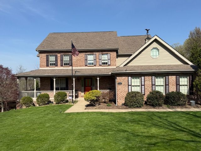 A large brick house with a large lawn in front of it