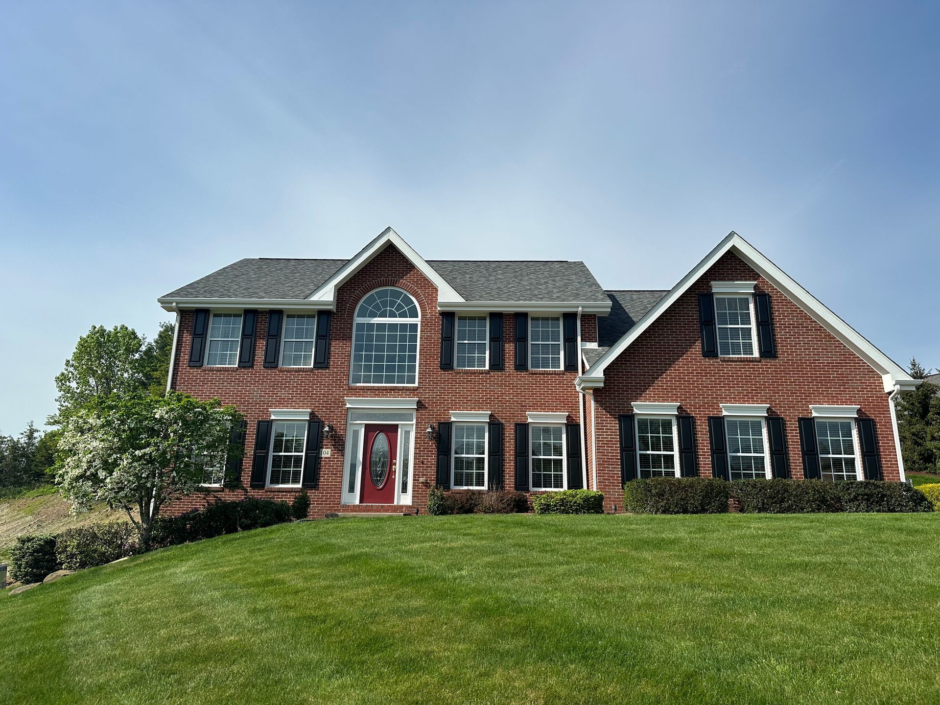 A large brick house with black shutters and a red door