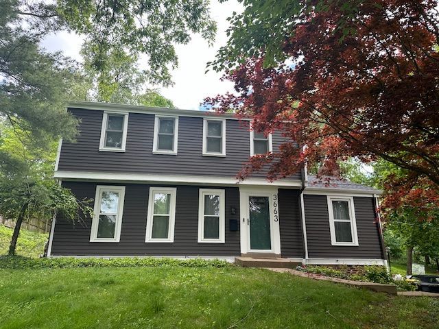 A house with a lot of windows and a tree in front of it