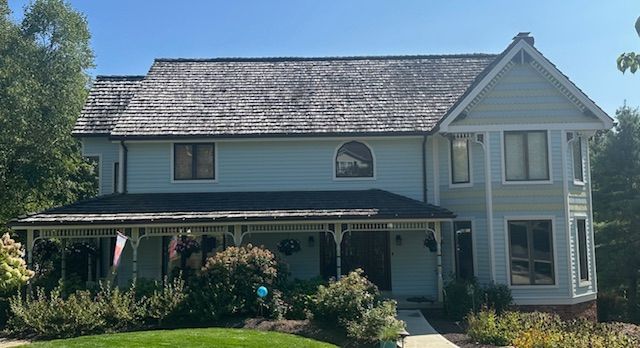 A large white house with a black roof and a porch.