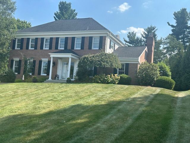 A large brick house with a lush green lawn in front of it